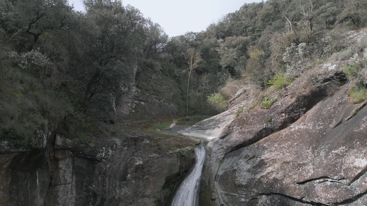 Clear water gracefully flows over the rocky cliffs of a small waterfall nestled in the serene forests near barcelona, catalonia, spain, creating a picturesque natural landscape