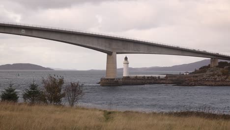 bridge taking you over the water with a light house driving towards isle of skye, highlands of scotland