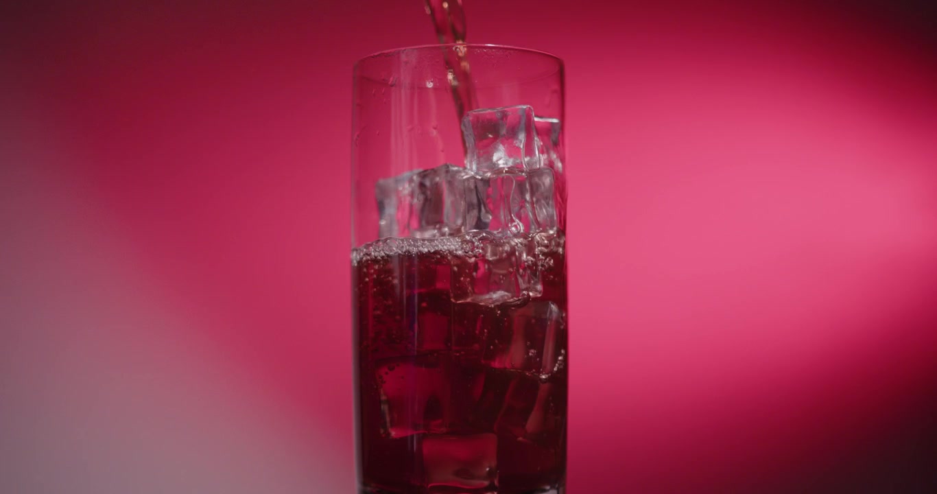 Bevanda rossa versata in un bicchiere con cubetti di ghiaccio (Clip per video di prodotti)