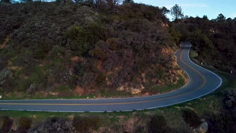 Curva-Cerrada-De-La-Carretera-De-Montaña-Al-Lado-De-Un-Acantilado-Al-Amanecer,-Drone-Revela