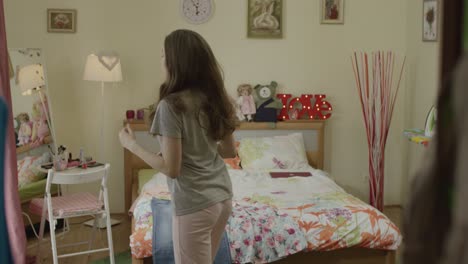 teenage girl jumping on bed in bedroom