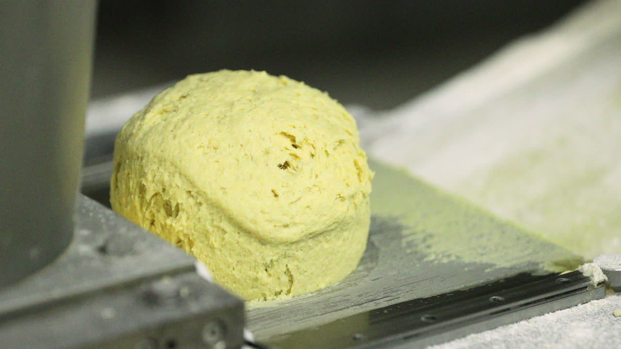 Impasto giallo in una macchina divisatrice e formatrice di pane in una panetteria - primo piano