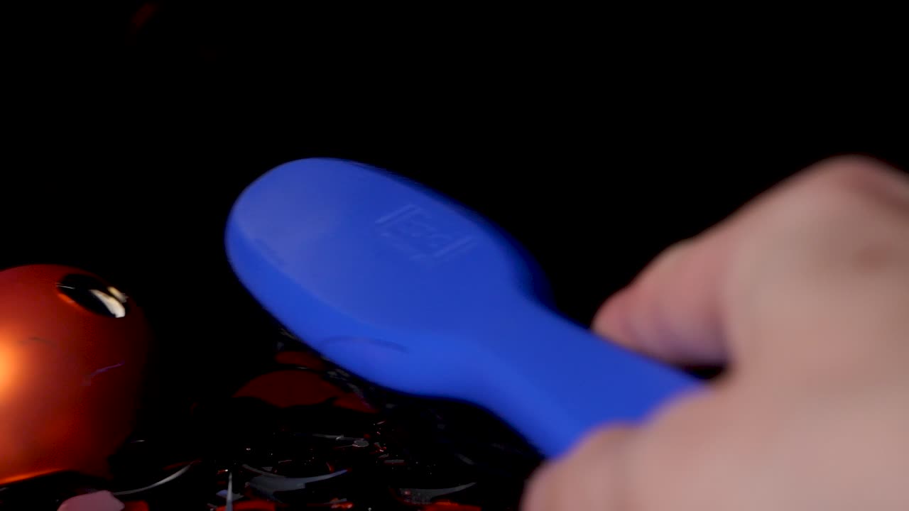 Una mano tiene un pennello blu e raccoglie le palline di Natale rotte.
