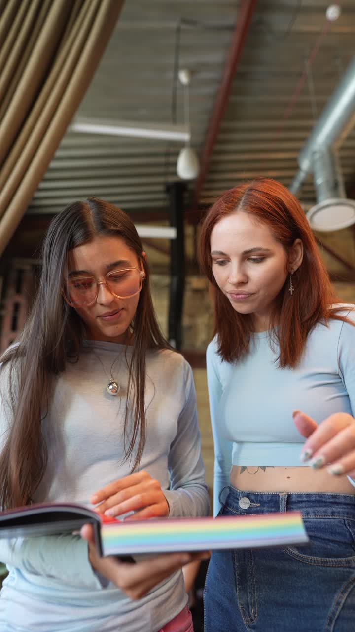 dos mujeres jóvenes mirando un libro en un café