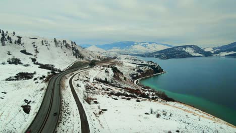 an aerial perspective of snow-covered landscape, traffic on highway 97, and turquoise wood lake