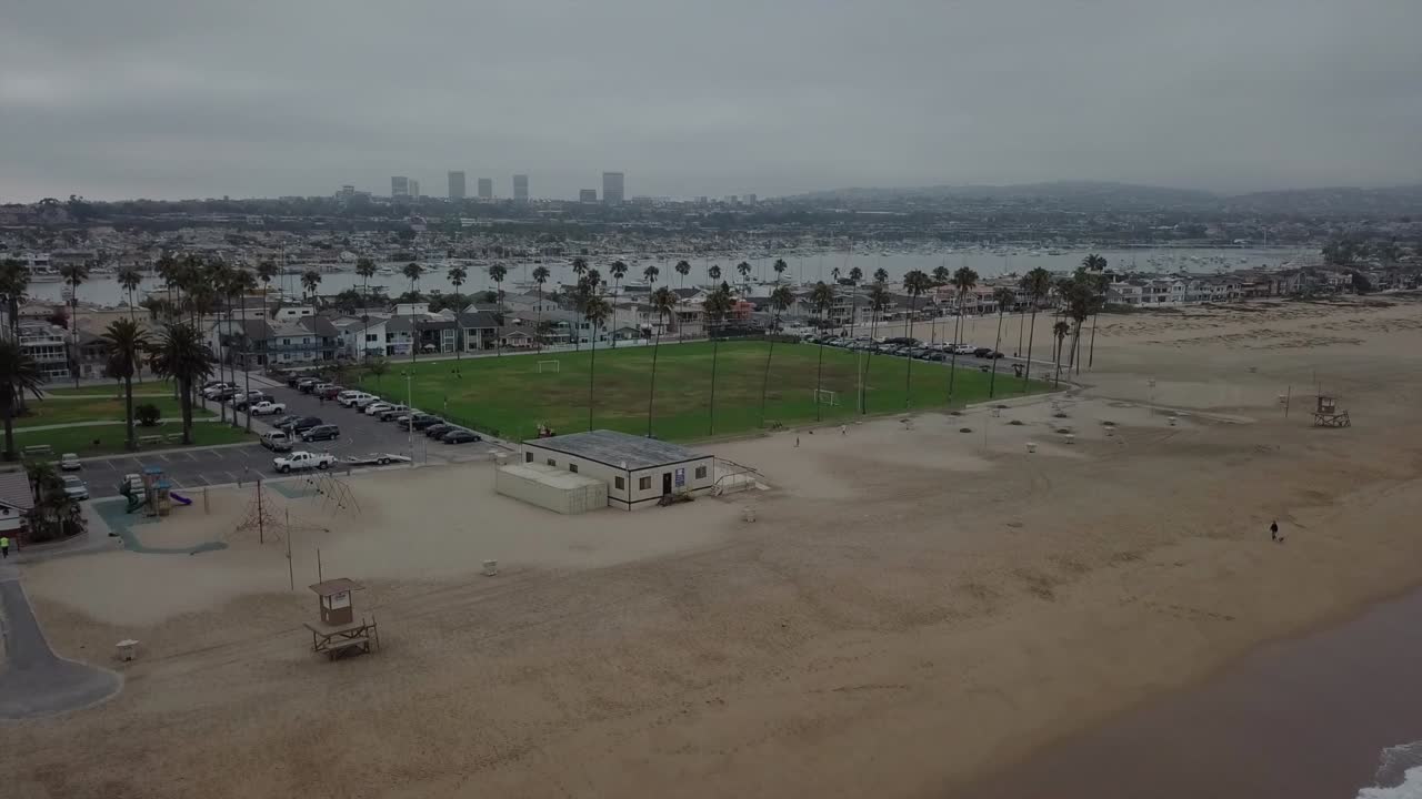 녹색 공원과 야자수가 있는 흐린 아침 서해안 해변은 정박지와 도시를 드러내는 공중 전망을 자랑합니다.