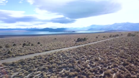 Beautiful-droneshot-watching-over-a-big-mountain-horizon-with-a-lake-at-it's-foot