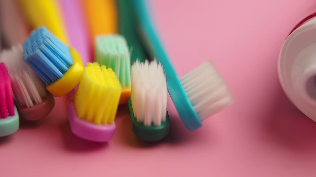 Colorful Toothbrushes and Toothpaste Tube on Pink Background