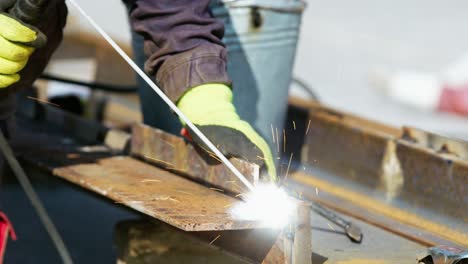 Close up slow motion of worker welding steel with bright sparks in industry