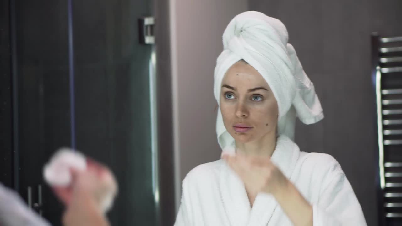 Young woman applying toner, using cotton disposable pads, skin care after shower