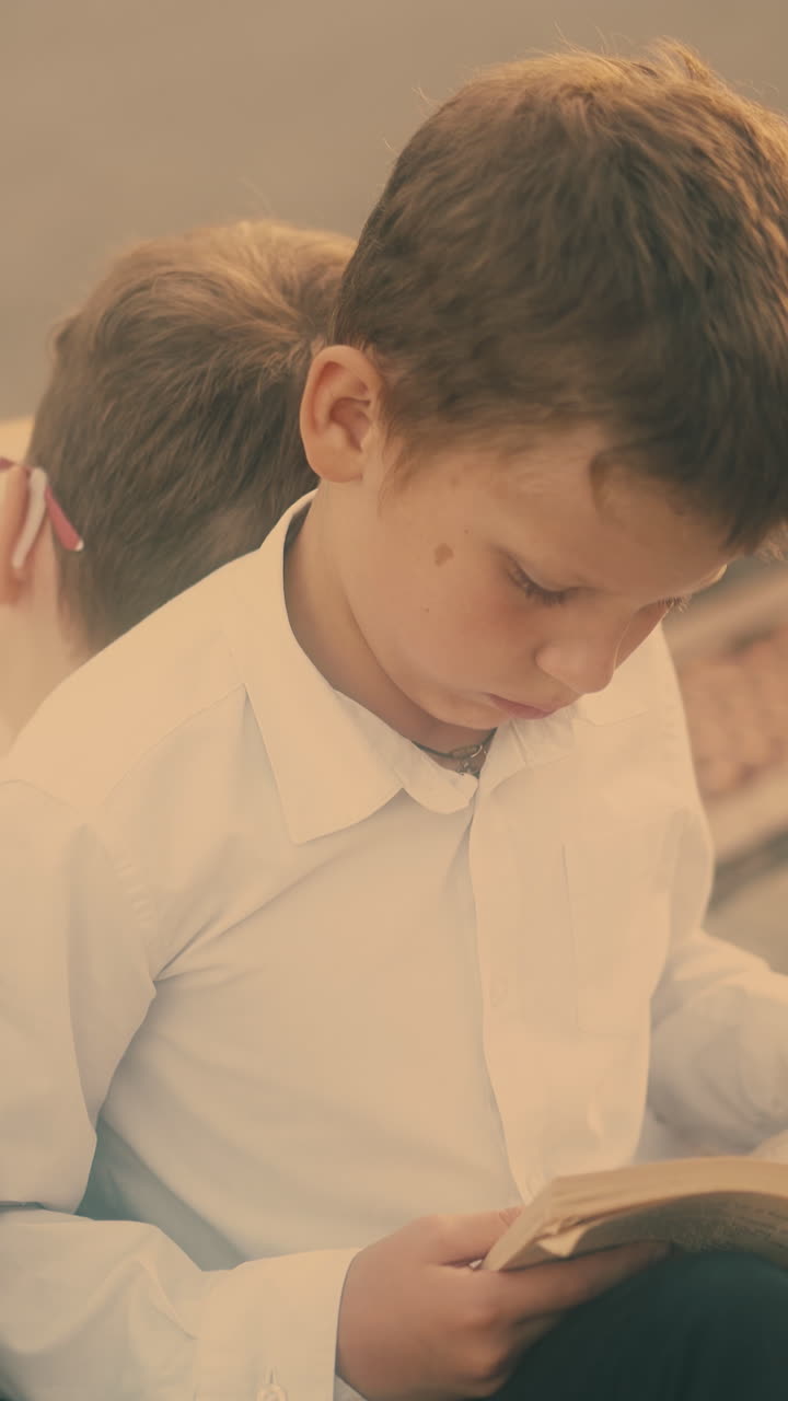 young serious guys study outdoors sitting on coloured schoolbags during preparation for exams closeup