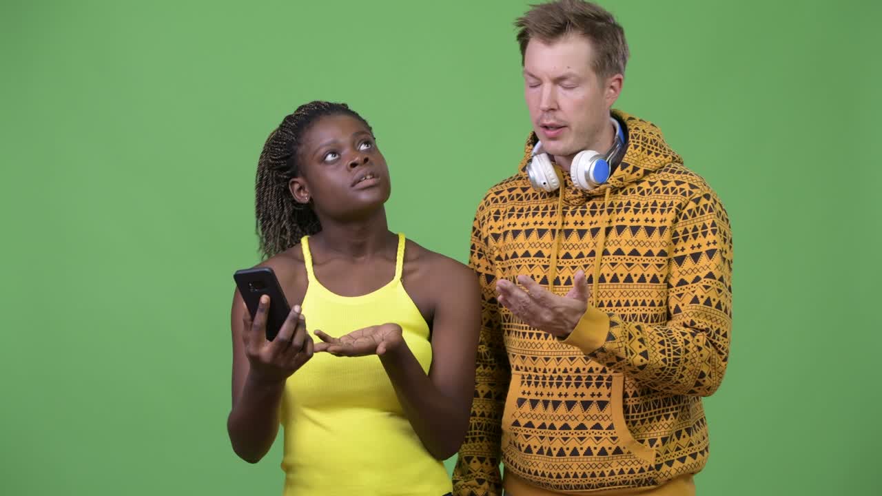 una joven pareja multiétnica usando el teléfono juntos.