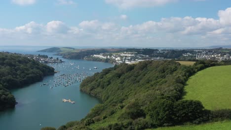 wide aerial sliding shot over the landscape surrounding the river fowey, revealing the cornish town of fowey in cornwall, uk