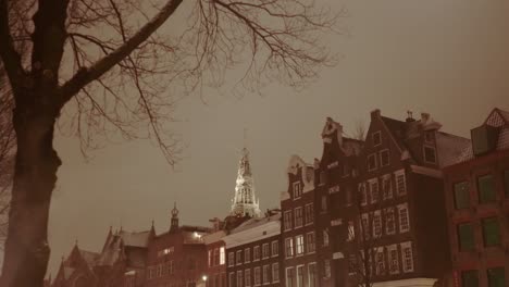 Amsterdamer-Grachtenhäuser-Und-Ein-Kirchturm-An-Einem-Kalten,-Nassen,-Nebligen-Winterabend