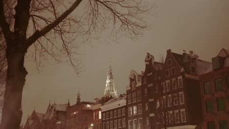 amsterdam canal houses and a church tower on a cold wet foggy winter evening