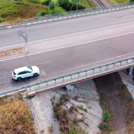 drone is flying over the road with a luxury car moving along the highway. beautiful white audi driving on the bridge. aerial view.
