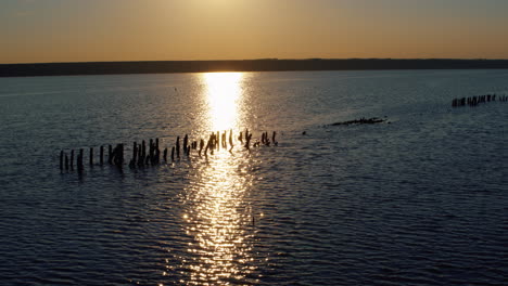 Vista-Aérea-Exploración-De-Extracción-De-Sal-Al-Atardecer-Naranja.-Superficie-Del-Agua-Del-Lago