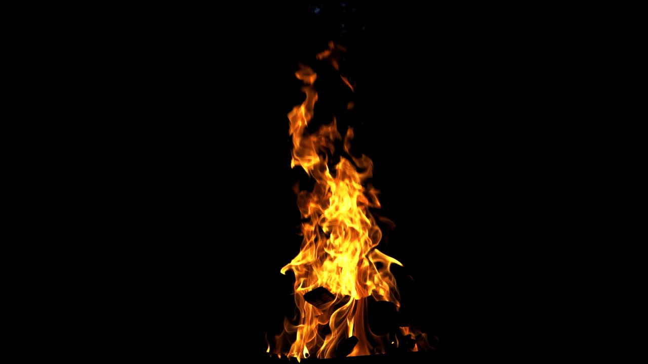 Fire burning in the slow motion isolated on dark background. Beautiful flame with logs burns brightly at night