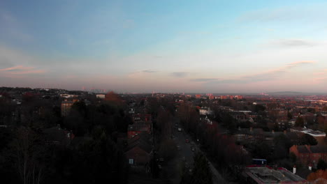 AERIAL-DOLLY-IN:-Drone-flying-above-Crystal-Palace-village-during-sunset-with-a-view-of-the-city-in-the-distance,-London-UK