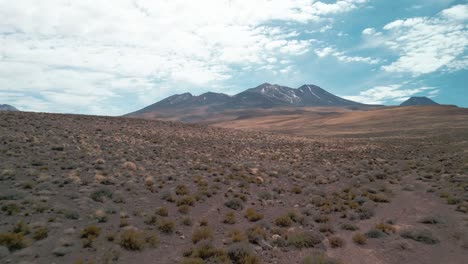 Drone-Aterrizando-En-Un-Paisaje-Remoto-En-El-Desierto-Chileno-Con-Un-Volcán-En-El-Fondo