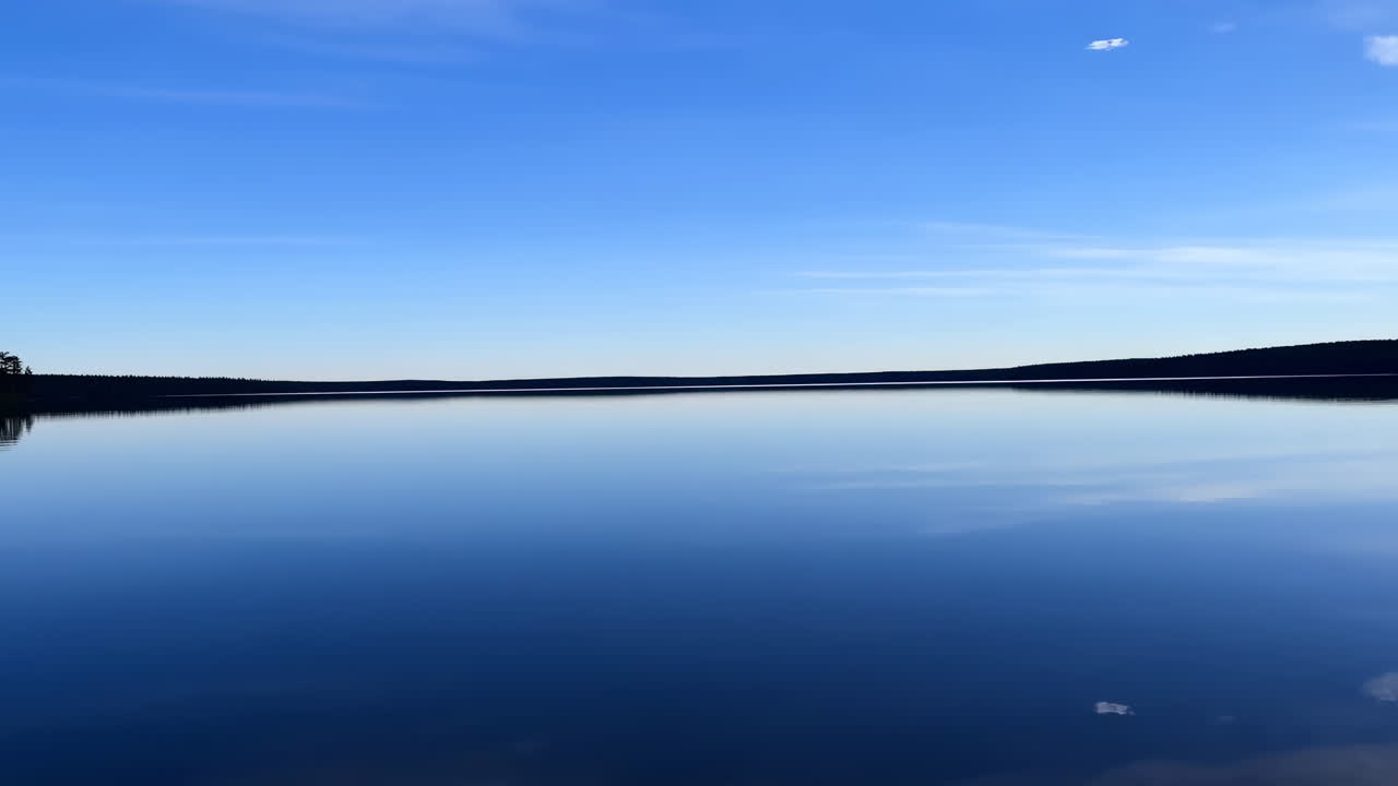 Lago sereno che riflette cielo blu e nuvole bianche