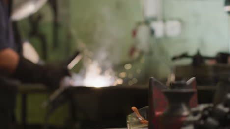 Caucasian-male-factory-worker-at-a-factory-standing-in-a-workbench,-welding