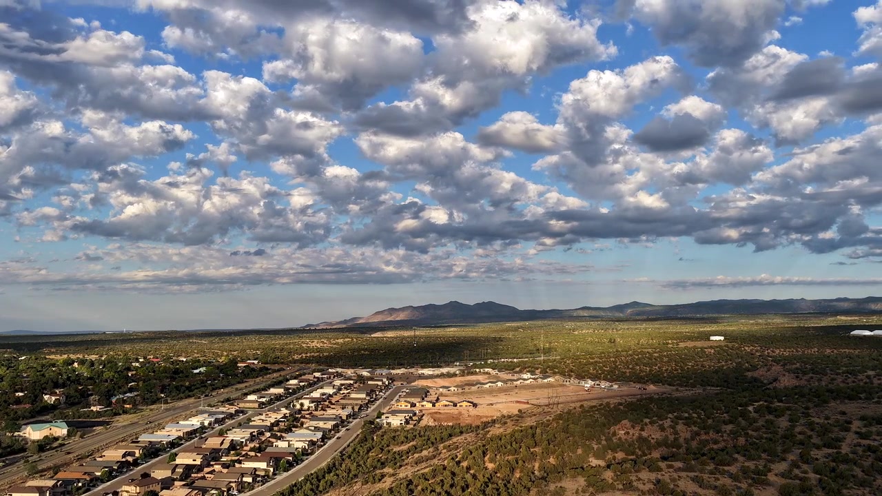 Timelapse 4K con drone che cattura la luce solare screziata e le ombre delle nuvole che si muovono splendidamente su un paesaggio desertico elevato. La vista include case residenziali a White Rock, Contea di Los Alamos.