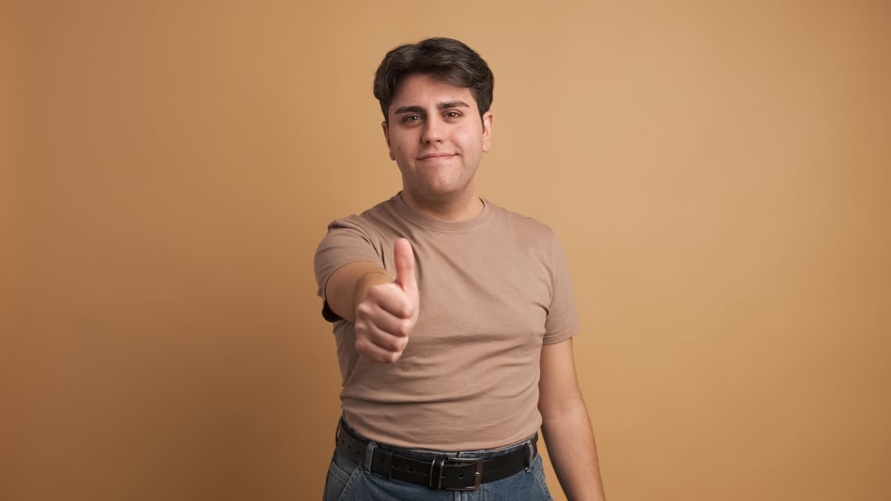 Young man gesturing agreement with thumb up