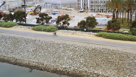 4k aerial rotating drone shot of a man exercising on a 10 speed bike riding to the beach during sunrise