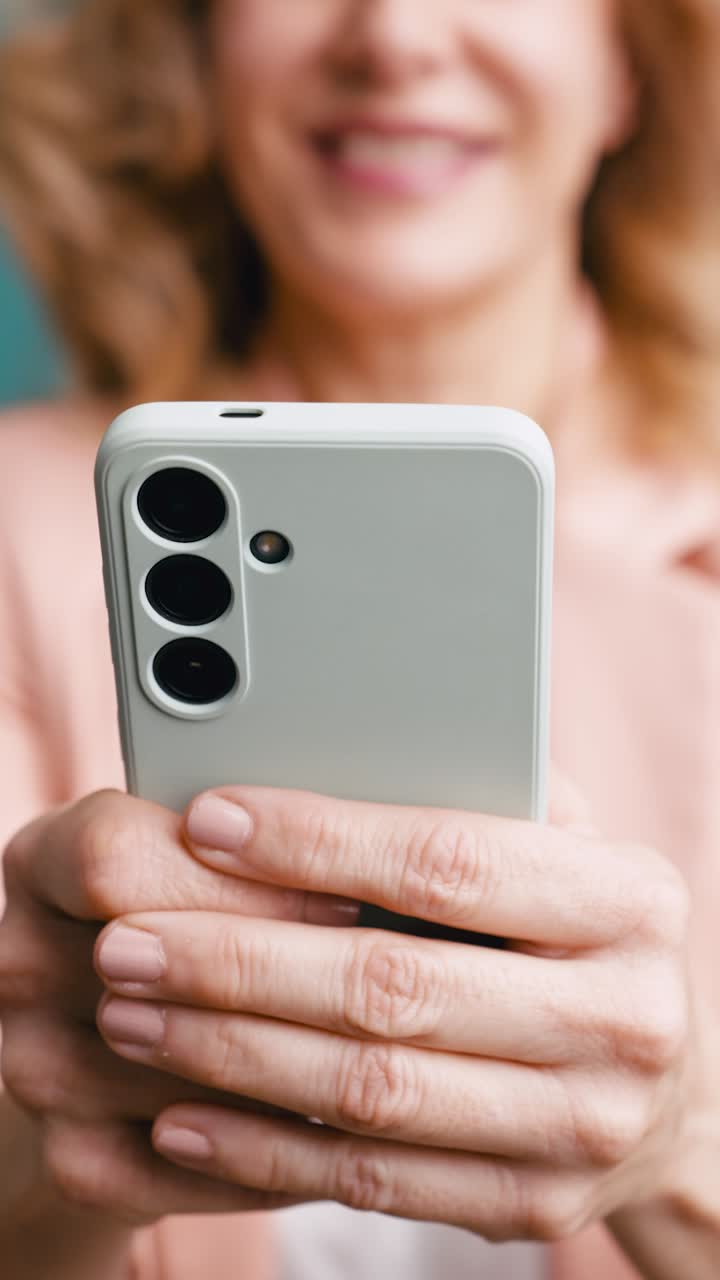 Primo piano di donna che tiene in mano uno smartphone e sorride