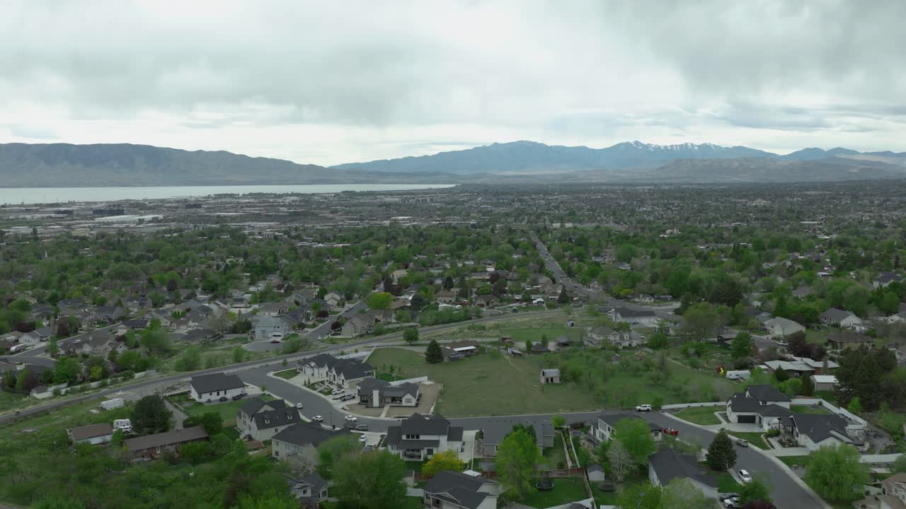 Area suburbana di Pleasant Grove, Contea di Utah, Utah, USA, con sviluppo residenziale a griglia vicino al Lago Utah e alle montagne Wasatch Front, all'interno del sistema Basin and Range, cielo coperto, ripresa aerea con drone in avanti.