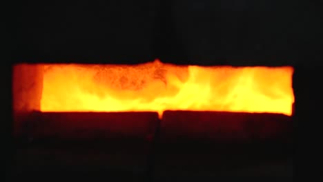 a large, intense flame is visible burning within a furnace, seen through a narrow slit