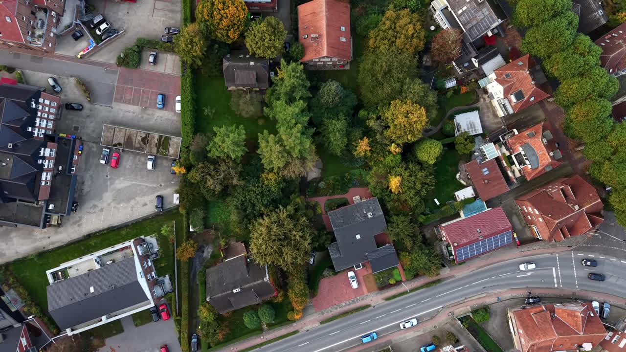 Case di un quartiere tedesco con tegole arancioni e alberi colorati in autunno. Auto parcheggiate, strade e veicoli sulla carreggiata all'ora del tramonto. Scena tranquilla in una piccola cittadina
