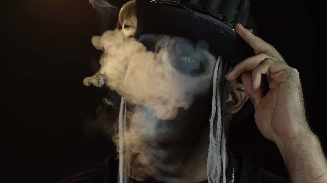 hombre siniestro con horrible halloween vacaciones esqueleto maquillaje levantando la cabeza y fumando cigarro