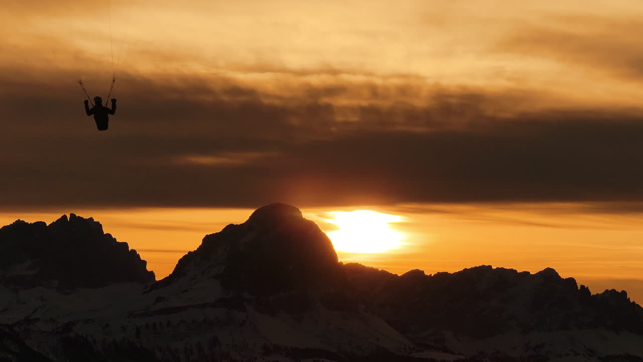Paragliding at Sunset over Snowy Mountains