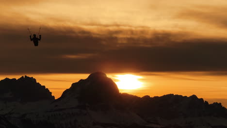 paragliding at sunset over snowy mountains