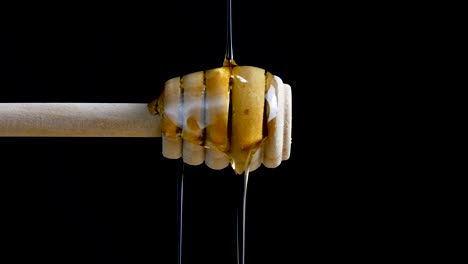 Pouring honey to dripper stick againt black blackground