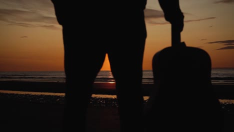 hombre corriendo con guitarra en la playa de arena trasera al atardecer-26