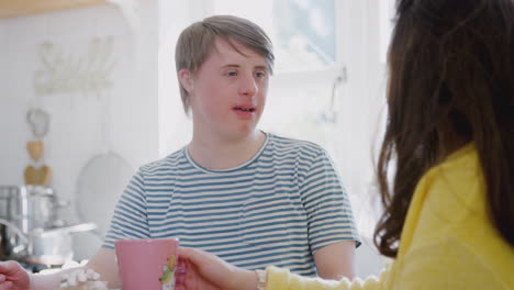 young downs syndrome couple enjoying hot drink in kitchen at home