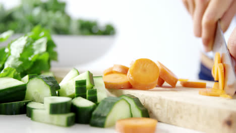 mid-section of woman cutting vegetables on chopping board