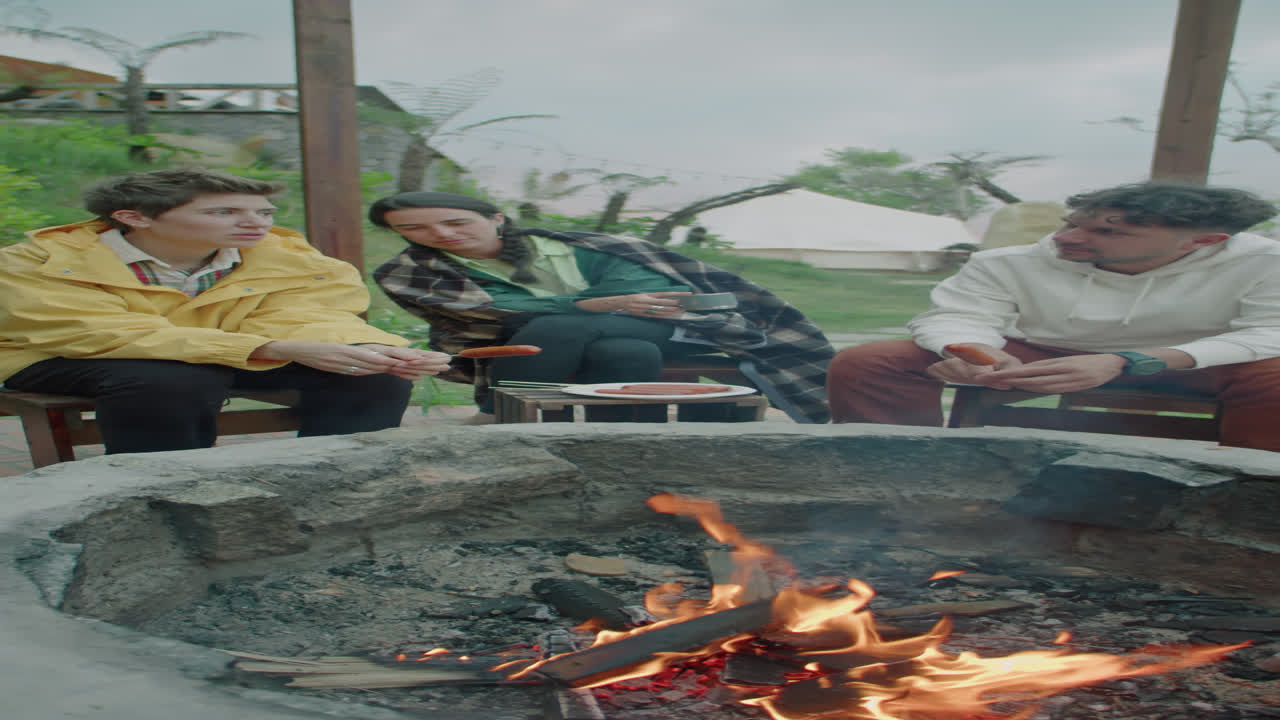 Tourists Resting by Campfire, Having Meal and Chatting at Glamp