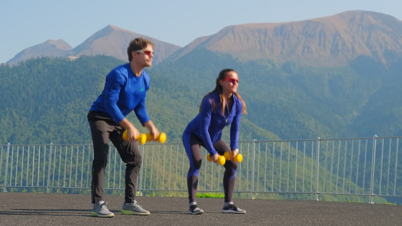 pareja trabajando con pesas en las montañas