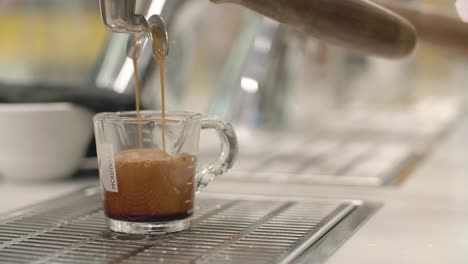 Low-closeup-of-coffee-slowly-filling-up-glass-cup-from-machine