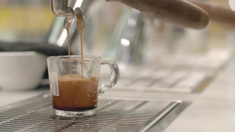 low closeup of coffee slowly filling up glass cup from machine