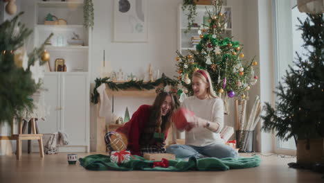 hermanas alegres lanzando regalos de navidad en casa