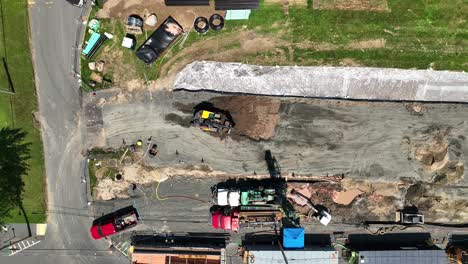 excavator backs up and spins as it removes dirt from pit, drone top down