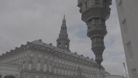 christianborg building in copenhagen with an upside down statue in the foreground on a cloudy day log