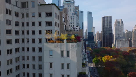 Slide-and-pan-footage-of-colourful-plants-on-terrace-in-top-stories-of-building.-High-rise-buildings-and-autumn-colour-trees-in-park.-Manhattan,-New-York-City,-USA