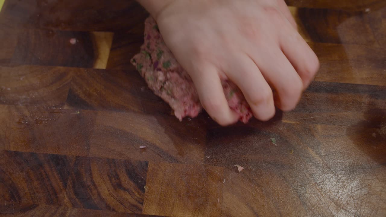 미트볼을 만들기 위해 나무 컷 보드에 고기를 매싱 손에 닫습니다