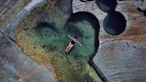 Piscina-De-Figura-8,-Australia,-Espiral-Ascendente-De-Drones,-Niña-Flotando-En-La-Piscina